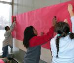 Students put up the background paper for their display boards at the Main Library.