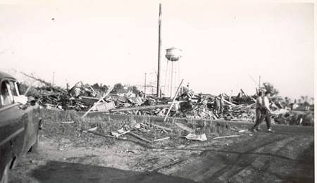 Field of debris with water tower in background.