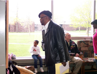 Man in leather jacket and hat lecturing. 