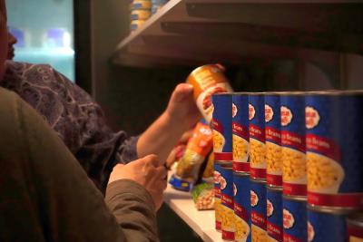 Hands reaching for canned goods in food pantry