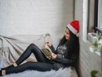 A woman reading a book while wearing a Santa hat 