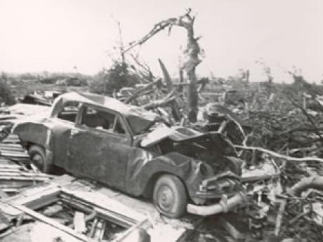 Smashed car in field of tornado wreckage. 